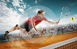 The one jumping player, caucasian fit man, playing tennis on the earthen court with spectators