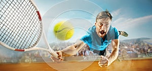 The one jumping player, caucasian fit man, playing tennis on the earthen court with spectators