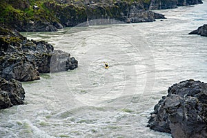 One kayaker on a yellow kayak floats on the mountain river Katun.