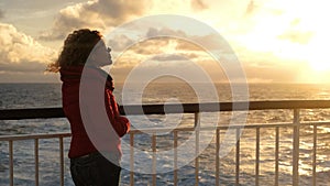 One lady with red winter warm jacket enjoy the sunset on the cruise boa deck during ocean travel, Transport and traveler people