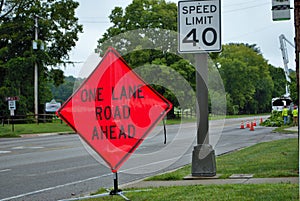 One lane road ahead construction sign on the side of a five lane road