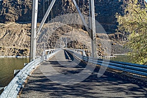 A one-lane suspension bridge spans across the Deschutes River at Cove Palisades State Park, Oregon, USA