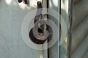 One large brown iron padlock hanging on a gray wooden door