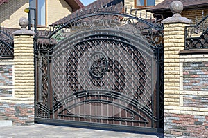 One large brown metal gate with a black wrought iron pattern on a brick wall