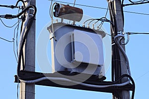 One large iron transformer with electrical wires on two gray concrete pillars