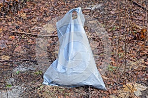 one large ragged gray plastic bag with garbage