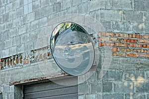 One large round observation mirror hangs on a gray brick wall