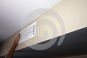One Left Hand on a Closed White Rectangle Wall Air Duct Vent