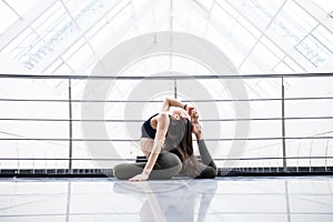 One-Legged King Pigeon Pose. Beautiful yoga woman practice in a big window hall background. Yoga concept.