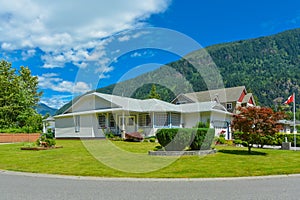 One level rancho house with Canadian flag on a front yard on blue sky background photo