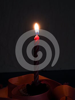 One light candle burning brightly in the black background