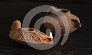 One Lit and One Unlit Handmade Oil Lamps on a Dark Wood Table