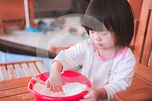 One little Asian girl age 2-3 years old. She is doing flour making Patongko activities.