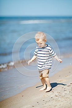 One little beautiful kid walking along the seashore at the day time