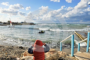 One little boy in jacket with hood watching at storm sea during winter leisure outdoor travel