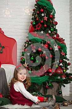 One little Caucasian cute girl smiling with present box in his hand in the festive New year studio room