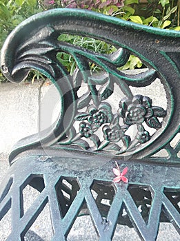 One little flower on green ironcast garden bench