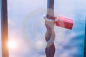 One love lock or love padlock in front of a lake with sun reflection flares. Close up