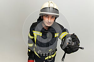 One male firefighter dressed in uniform posing over white studio background.