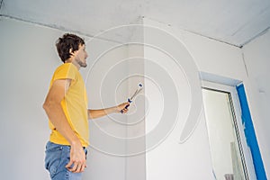 One male house painter worker painting and priming wall with painting roller. DIY