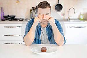 One man dieting and tempted by chocolate muffin