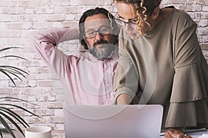 One man having relax stretching shoulder at office while woman colleagues use his computer. Small business team couple concept