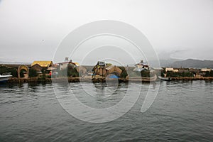 One of the man made islands of Lake Titicaca in Peru, South America with many boats in fronts of it