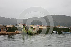 One of the man made islands of Lake Titicaca in Peru, South America with traditionally made boats in fronts of it