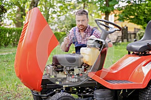 One man repairing broken lawn mower engine in the garden