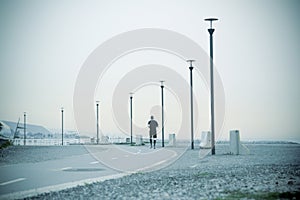 One man running next to the road. Perspective and vanishing point. Some street lights at sunrise. Empty copy space for Editor`s te