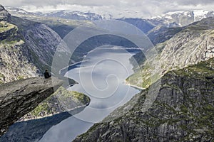 One man sitting on trolltunga troll`s tongue rock , Norway