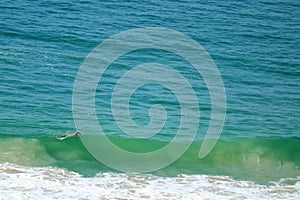 One man swimming in big waves of Atlantic ocean at Copacabana beach in Rio de Janeiro, Brazil