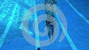 One man swimming in a deep pool underwater