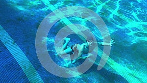 One man swimming in a deep pool underwater