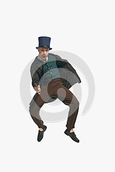 One man wearing vintage clothes, cylinder hat holding fake gun and jumping over white studio background. Dangerous guy