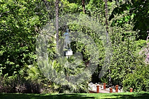 One of many of statue amount tropical vegetation in Jardines del Buen Retiro, Madrid, capital of