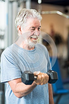 One mature man doing exercise holding one dumbbell alone in the gym to be fit and healthy - lifestyle and concept - senior or