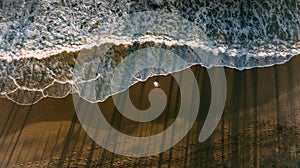 One men stay on the beach. Wave and shadow reflection from palms. Dark