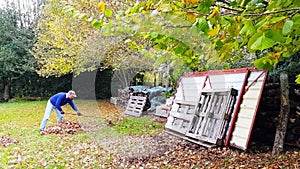 One midle age man collects fallen leaves .