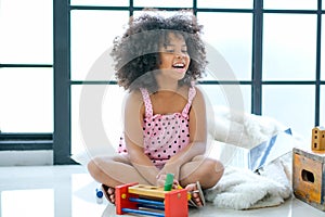 One mixed race African girl is smiling and sit on floor enjoy with the toys