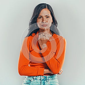 One mixed race woman  against grey studio background with copyspace. Young hispanic standing alone and thinking