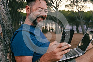 One modern adult man using and working on laptop at the park. Concept of smart working and freelance digital nomad small business