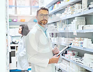 One moment while I fill your prescription. a mature man doing inventory in a pharmacy with his colleague in the