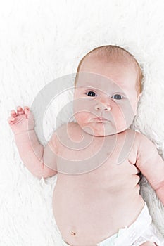 A one month old baby girl wearing a white diaper cover. Shot from overhead on a white background