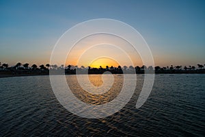 One more perfect sunset. Sunset on sea coast with palm trees and sun reflection water. Silhouette of palm trees tropical