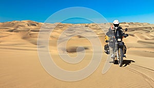 One motorbiker driving in sand dune desert. Motorcycle Adventure in Namib Desert, Namibia.