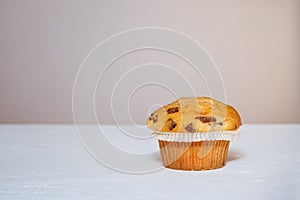 One muffin with chocolate peices on a white table