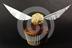 One muffin with Golden Snitch decoration on black background. Harry Potter theme photo