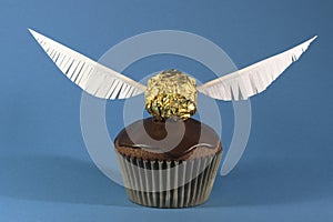 One muffin with Golden Snitch decoration on blue background. Harry Potter theme photo