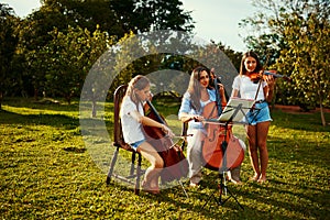 We are one musical family. Shot of a beautiful mother playing instruments with her adorable daughters outdoors.